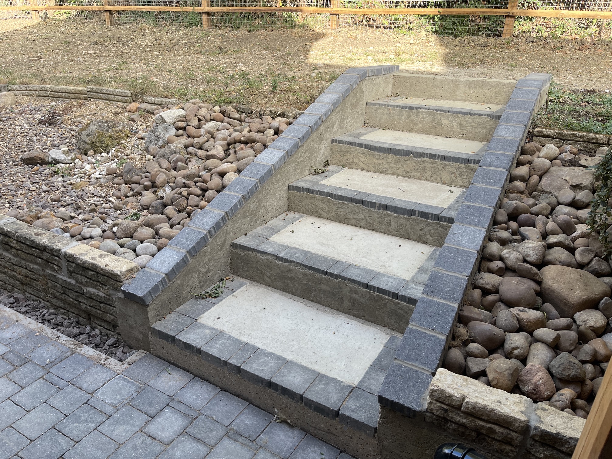 Block-paved garden steps with pale stone treads and dark contrast edging between rockery borders