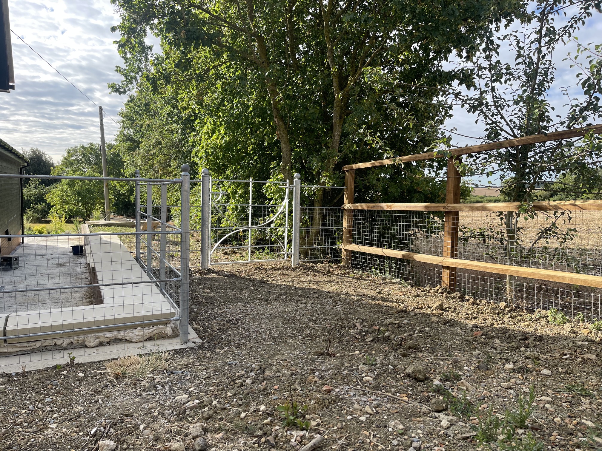 Galvanised metal estate gate with wire mesh and new timber post-and-rail fence