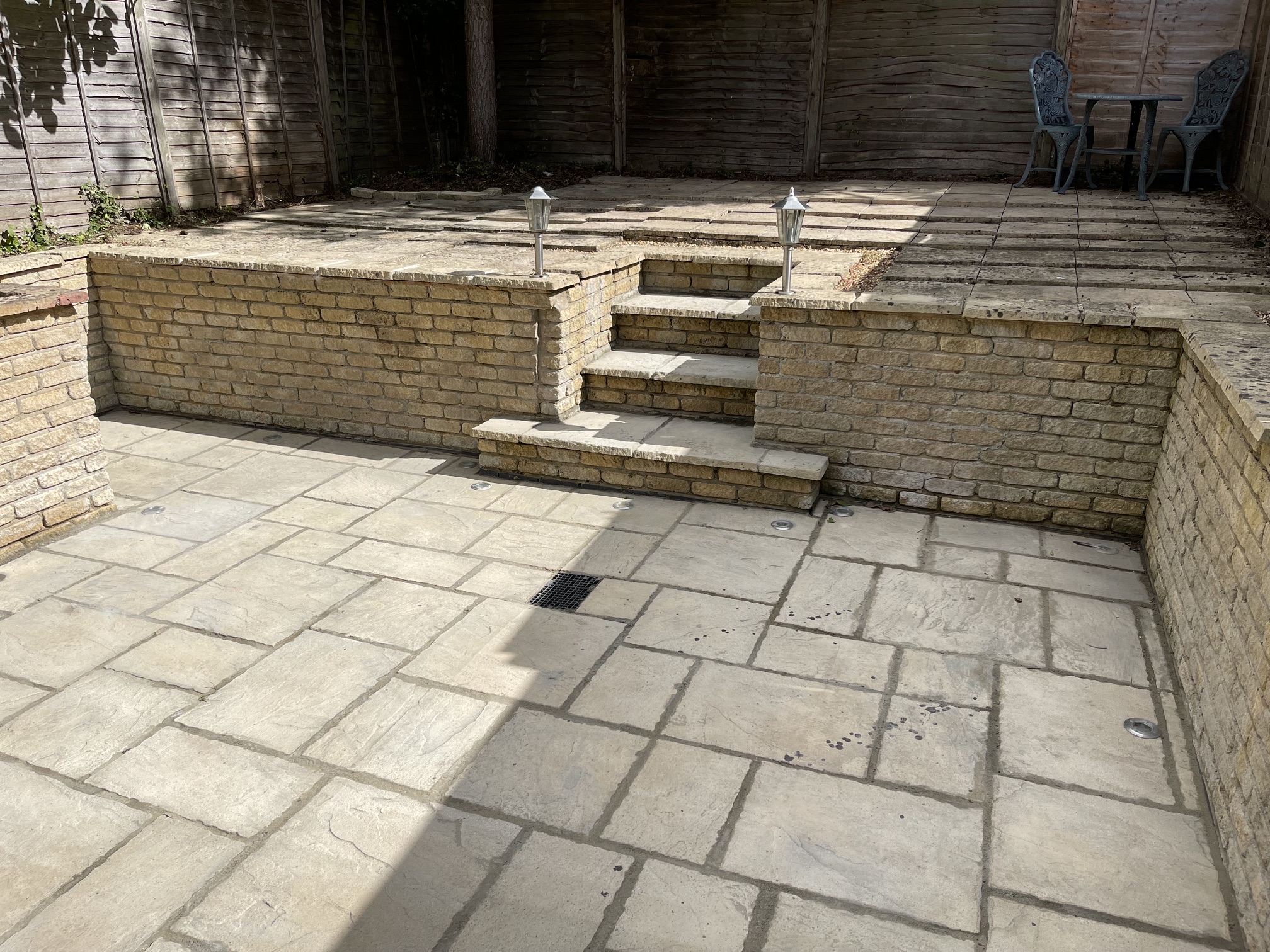 Tiered courtyard patio with brick retaining wall, stone steps and sandstone paving